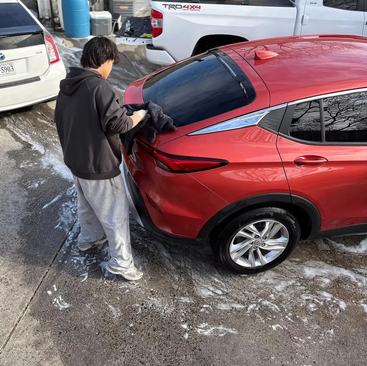 DMV Luxury Detail team member hand-finishing a red Lexus during a mobile detailing appointment