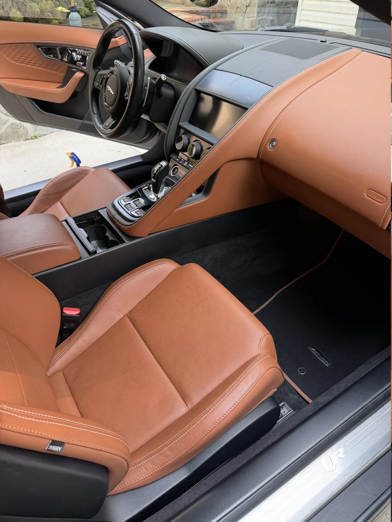 Freshly detailed Jaguar cabin with clean tan leather, dashboard, and carpeting