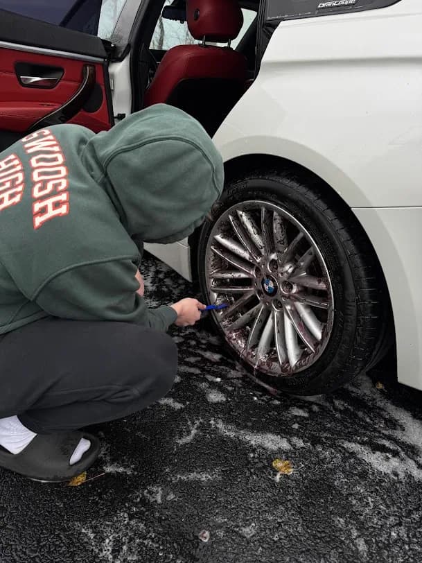 DMV Luxury Detail technician deep-cleaning a BMW wheel at a customer location